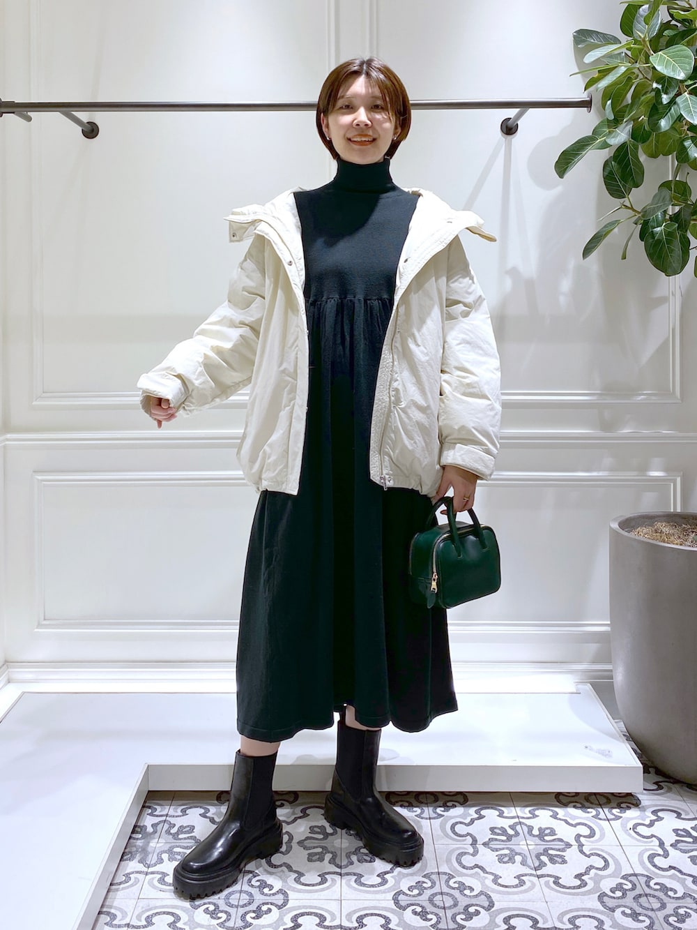 グリーン系のワンピース、ホワイト系のダウンジャケット/コート、ブラック系のブーツを着用したレディースの冬コーディネートの2枚目の写真