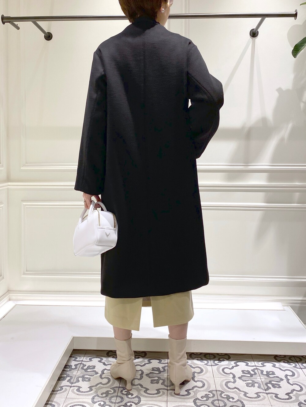 ブラック系のノーカラーコート、ブラック系のニット/セーター、ブラック系のTシャツ/カットソーを着用したレディースの秋コーディネートの5枚目の写真