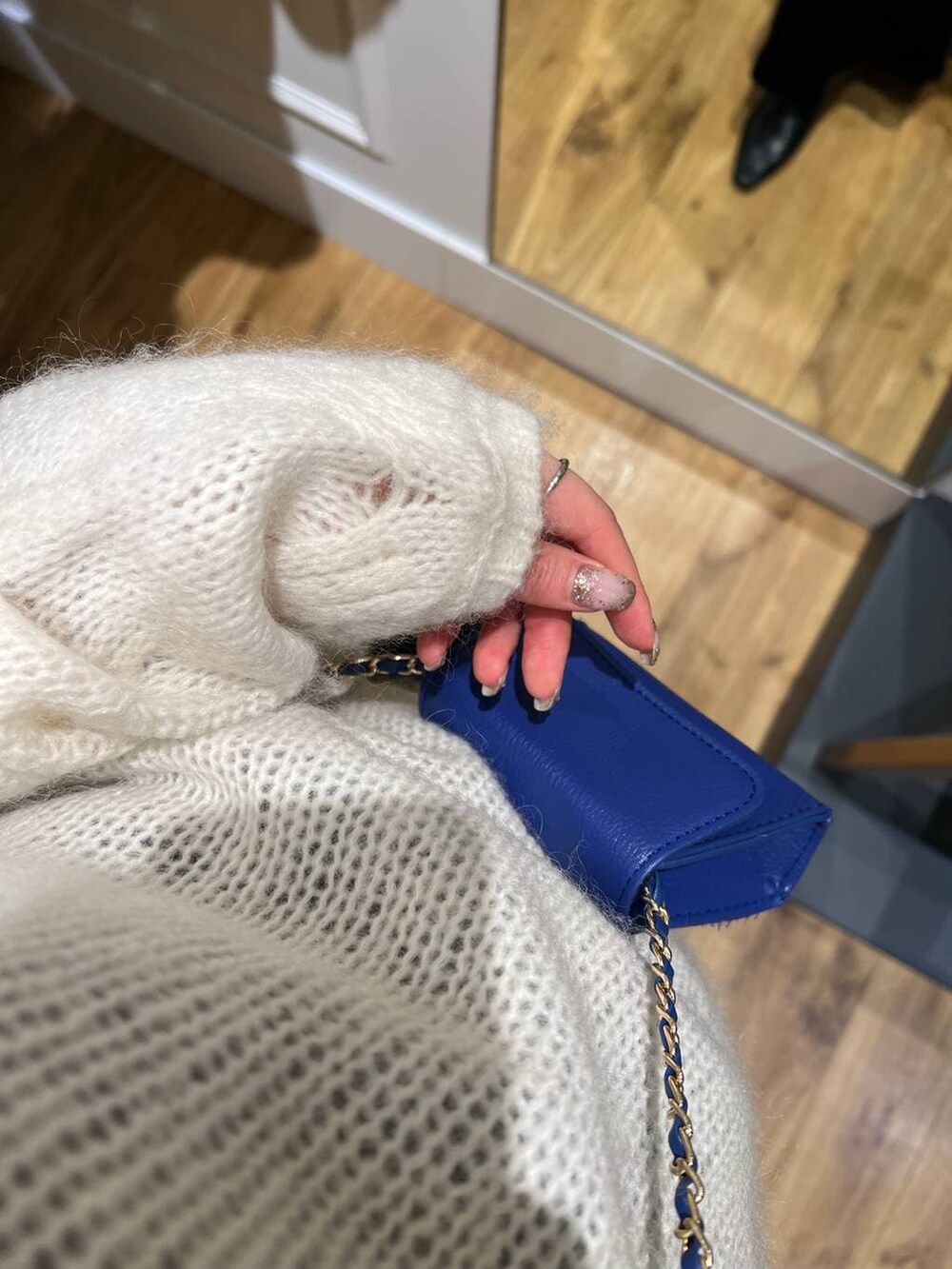 ホワイト系のニット/セーター、ブルー系のショルダーバッグ、ブラック系のスカートを着用したレディースの冬コーディネートの2枚目の写真