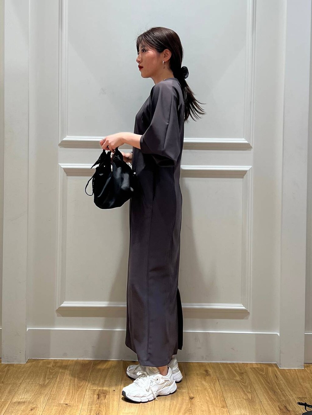 グレー系のワンピース、ブラック系のショルダーバッグ、シルバー系のネックレスを着用したレディースの春コーディネートの2枚目の写真