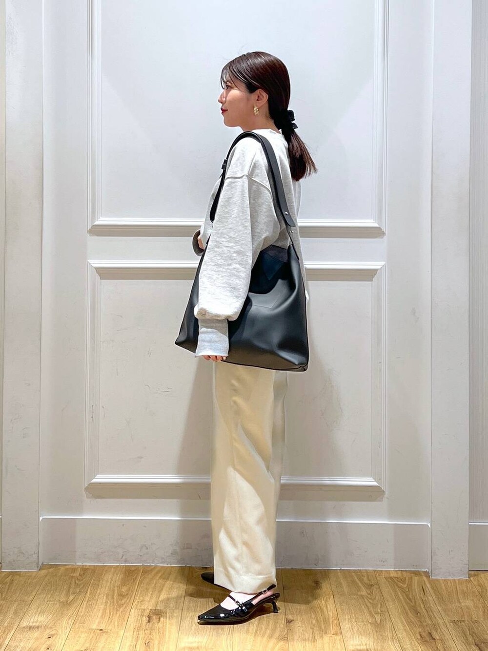 ブラック系のパンプス、グレー系のスウェット、ベージュ系のスラックスを着用したレディースの春コーディネートの2枚目の写真