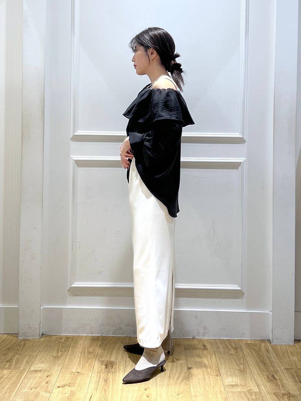 ブラック系のシャツ/ブラウス、ブラウン系のパンプス、ホワイト系のスカートを着用したレディースの秋コーディネートの2枚目の写真