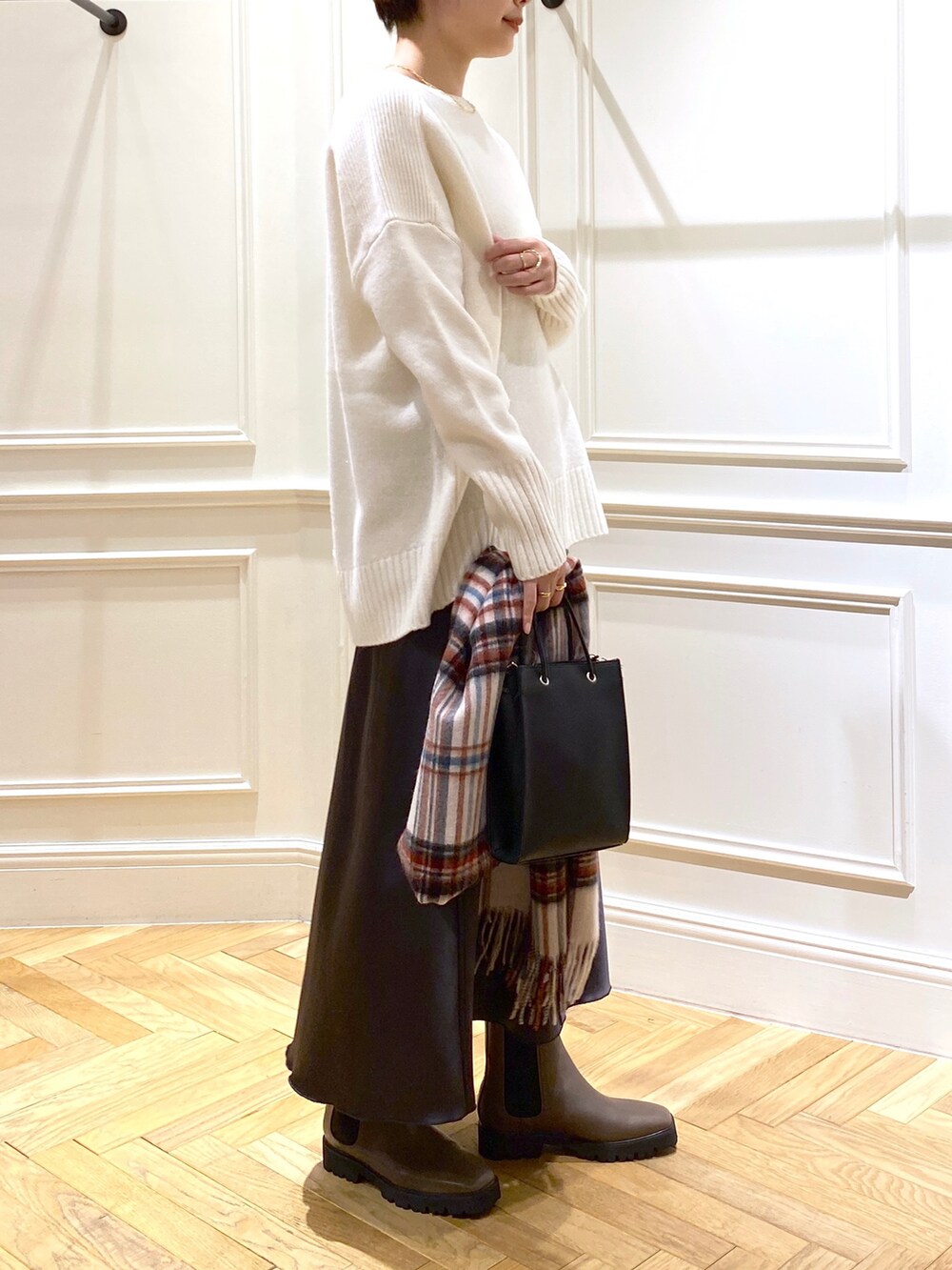 ホワイト系のニット/セーター、グレー系のスカート、ブラック系のショルダーバッグを着用したレディースの秋コーディネートの2枚目の写真