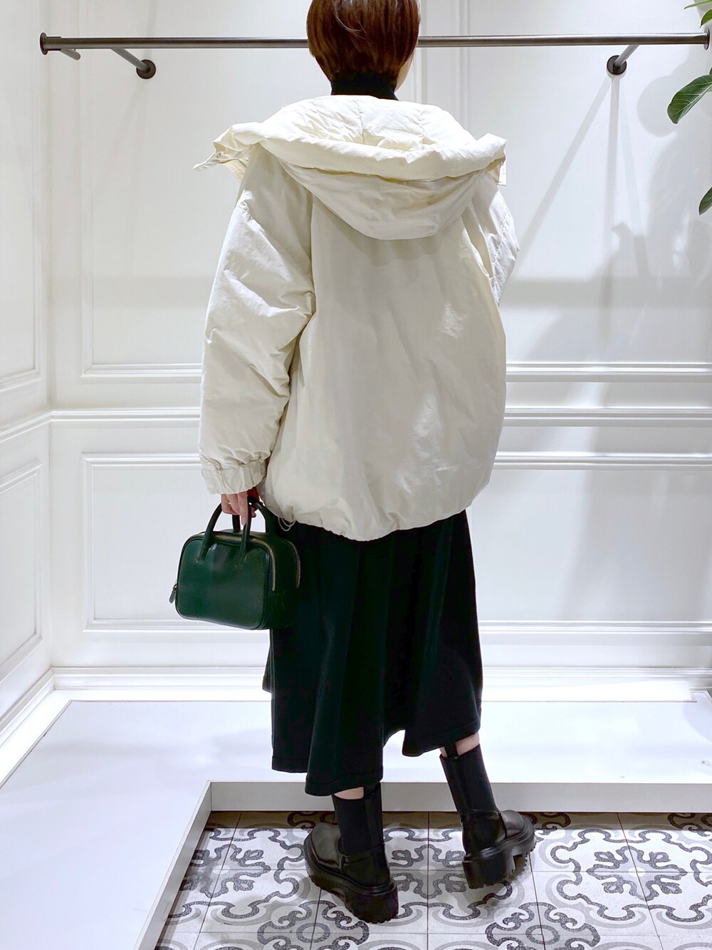 グリーン系のワンピース、ホワイト系のダウンジャケット/コート、ブラック系のブーツを着用したレディースの冬コーディネートの5枚目の写真