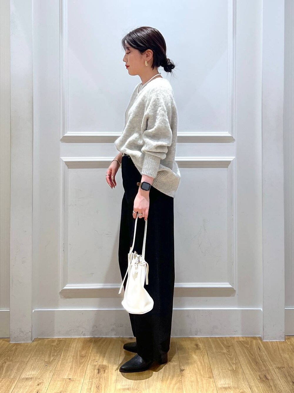 ブラック系のデニムパンツ、ブラック系のブーツ、グレー系のニット/セーターを着用したレディースの冬コーディネートの2枚目の写真