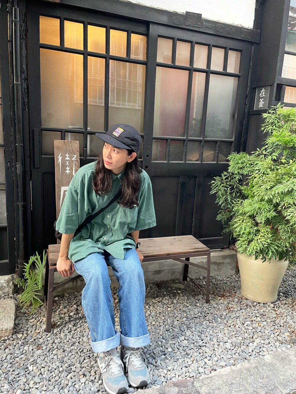 グリーン系のシャツ/ブラウス、ブルー系のデニムパンツ、グレー系のスニーカーを着用したレディースの秋コーディネートの5枚目の写真