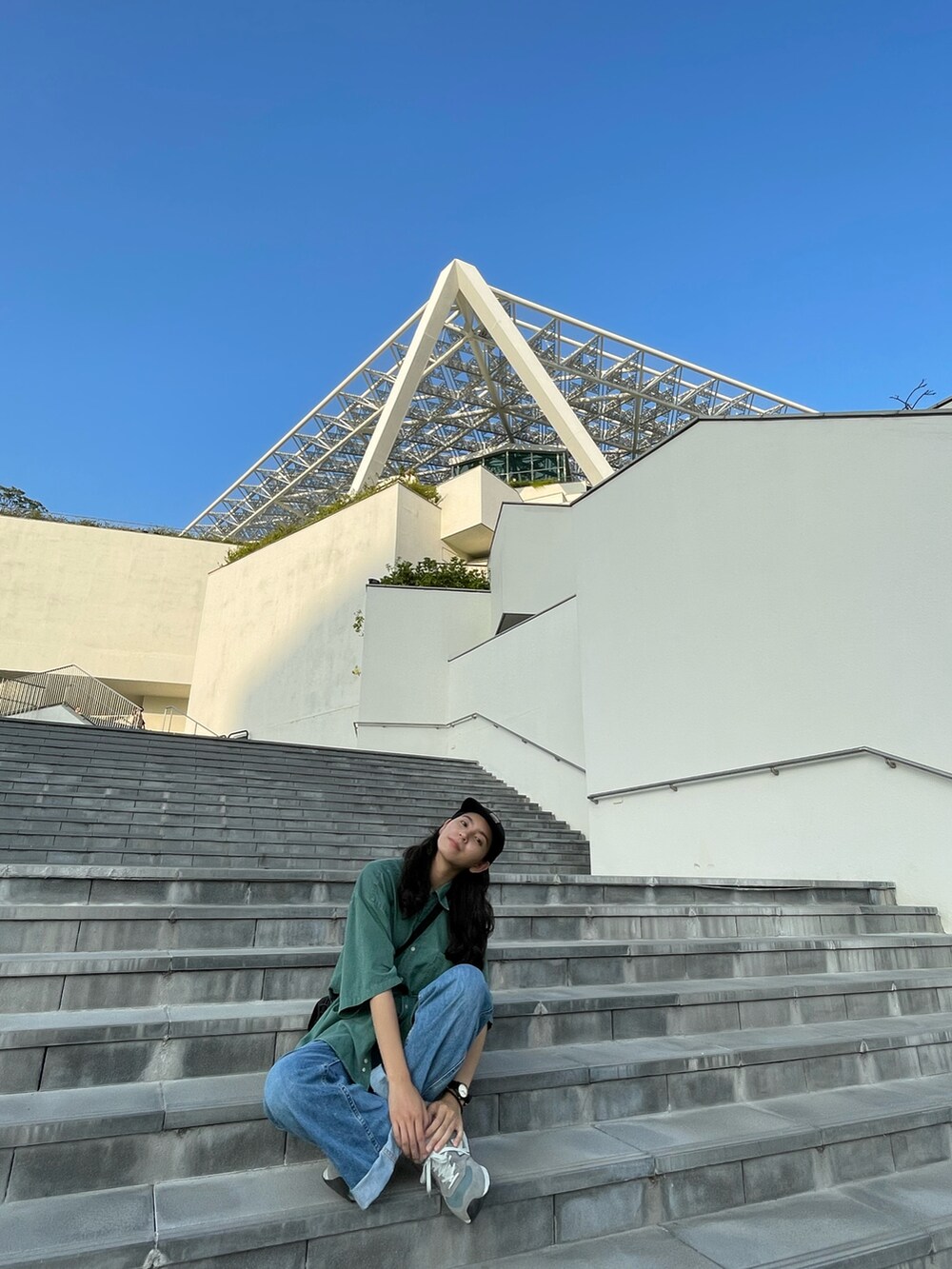 グリーン系のシャツ/ブラウス、ブルー系のデニムパンツ、グレー系のスニーカーを着用したレディースの秋コーディネートの2枚目の写真