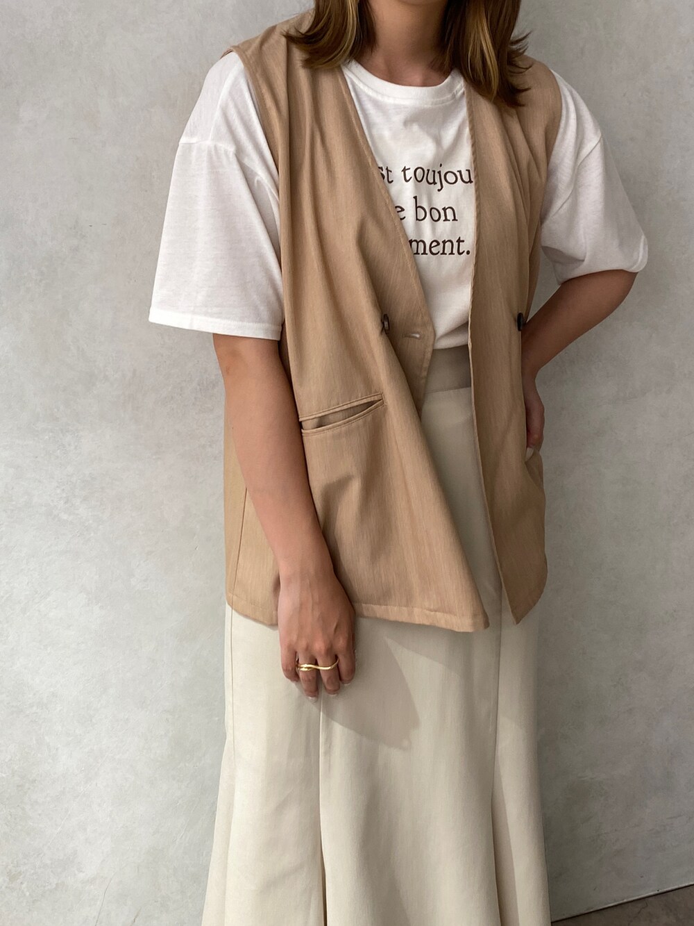 ホワイト系のTシャツ/カットソー、ベージュ系のベスト、ホワイト系のスカートを着用したレディースの夏コーディネートの2枚目の写真