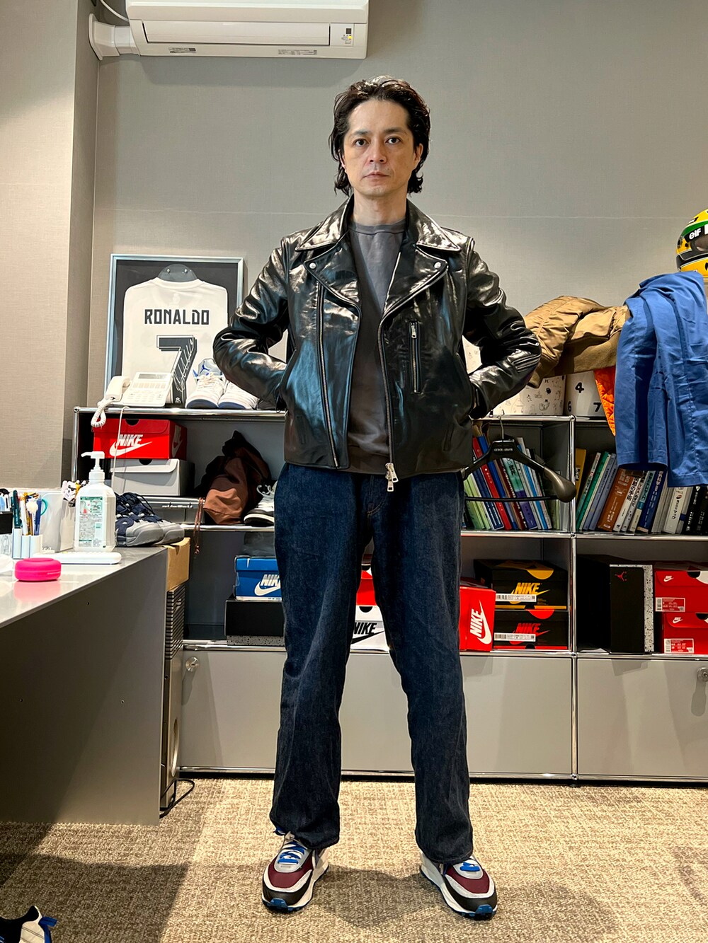 ブラック系のライダースジャケット、ブルー系のデニムパンツ、その他のスニーカーを着用したメンズの春コーディネートの3枚目の写真