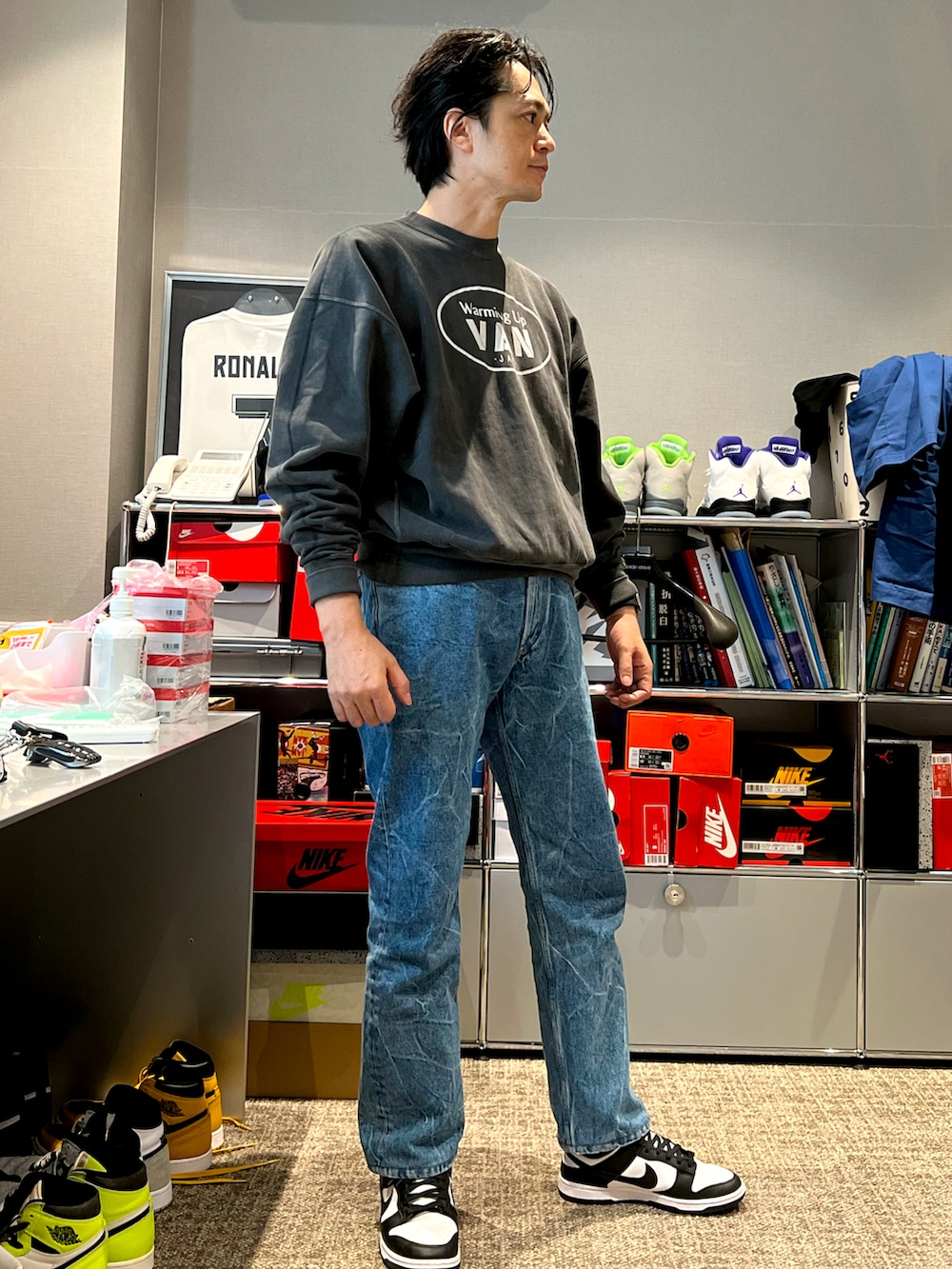 グレー系のスウェット、ブルー系のデニムパンツ、ブラック系のスニーカーを着用したメンズの秋コーディネートの3枚目の写真