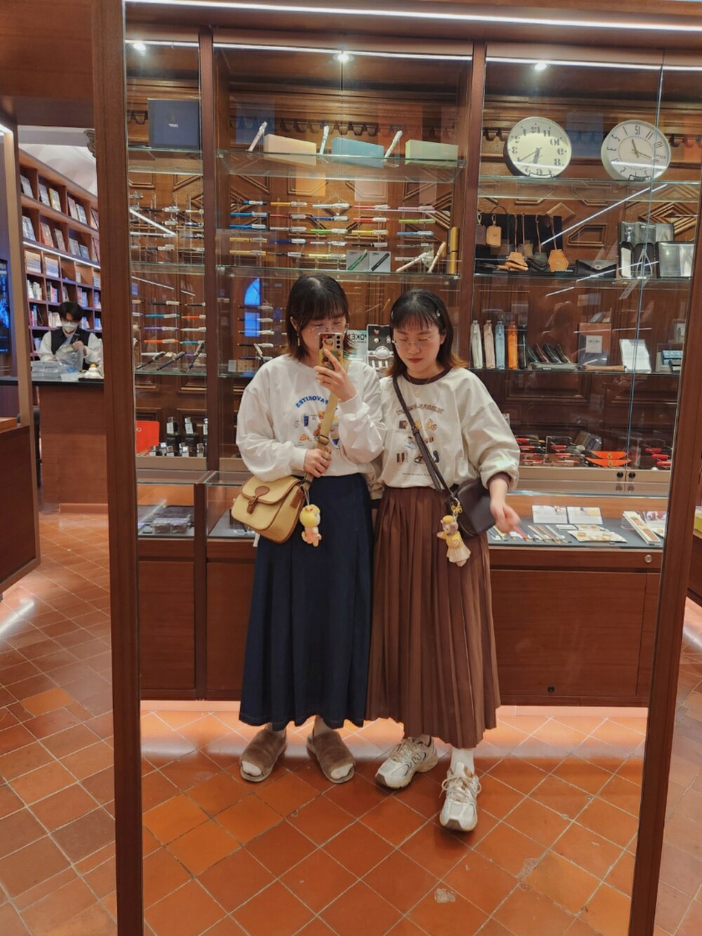 ベージュ系のTシャツ/カットソー、ブラウン系のスカート、ホワイト系のスニーカーを着用したレディースの秋コーディネートの2枚目の写真