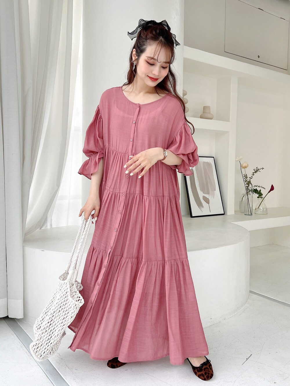 ピンク系のワンピース、ブラウン系のパンプス、ブラック系のヘアゴムを着用したレディースの春コーディネートの2枚目の写真