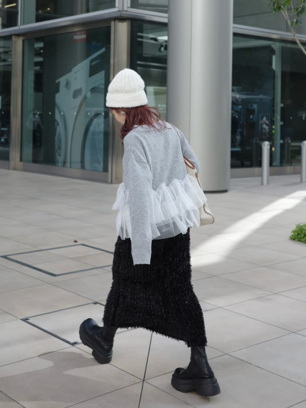 グレー系のニット/セーター、ブラック系のスカート、ブラック系のブーツを着用したレディースの秋コーディネートの3枚目の写真