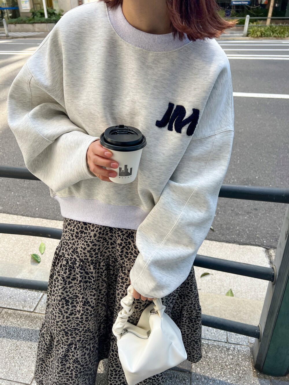 ホワイト系のスウェット、ホワイト系のハンドバッグ、ブラック系のスカートを着用したレディースの秋コーディネートの2枚目の写真