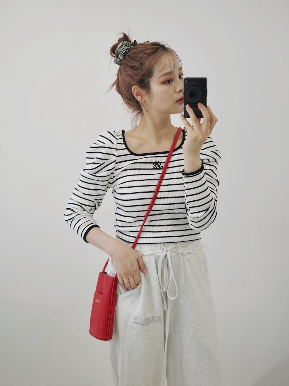 ベージュ系のサンダル、ホワイト系のスウェットパンツ、レッド系のショルダーバッグを着用したレディースの秋コーディネートの2枚目の写真