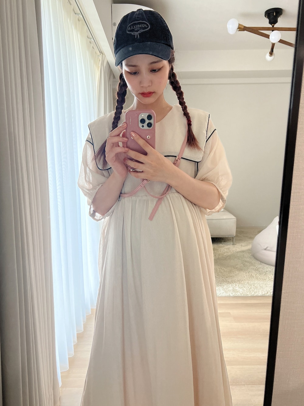 ホワイト系のワンピース、ベージュ系のキャップを着用したレディースの夏コーディネートの2枚目の写真