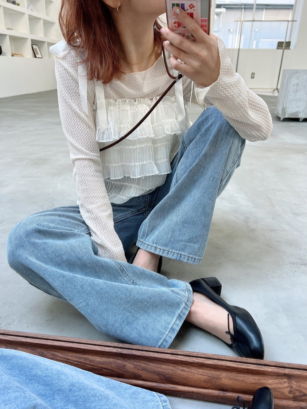 ベージュ系のニット/セーター、ブルー系のデニムパンツ、ホワイト系のハンドバッグを着用したレディースの春コーディネートの2枚目の写真