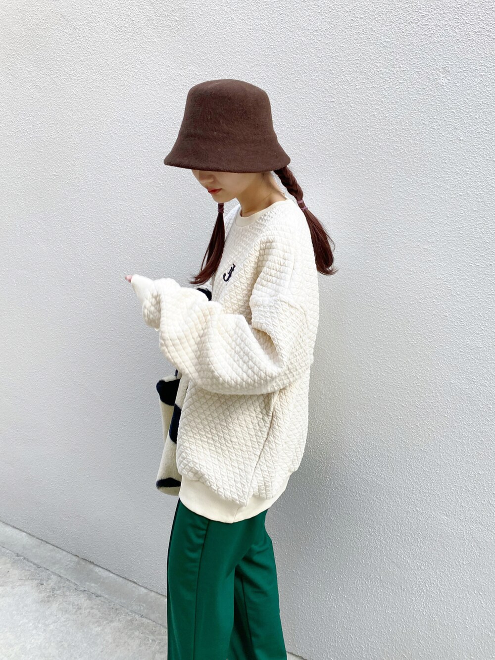 ベージュ系のスウェット、グリーン系のその他パンツ、ホワイト系のブーツを着用したレディースの冬コーディネートの2枚目の写真