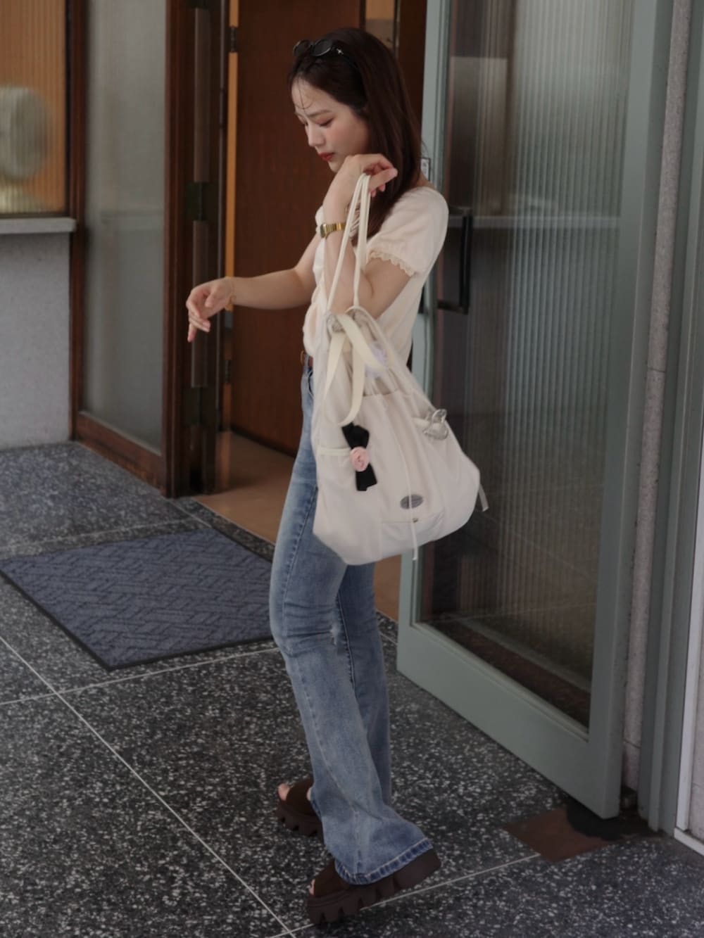 ブルー系のデニムパンツ、イエロー系のTシャツ/カットソー、ホワイト系のバックパック/リュックを着用したレディースの夏コーディネートの2枚目の写真