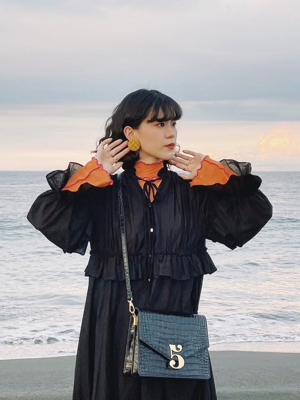 ブラック系のワンピース、オレンジ系のTシャツ/カットソー、ブラック系のショルダーバッグを着用したレディースの夏コーディネートの2枚目の写真