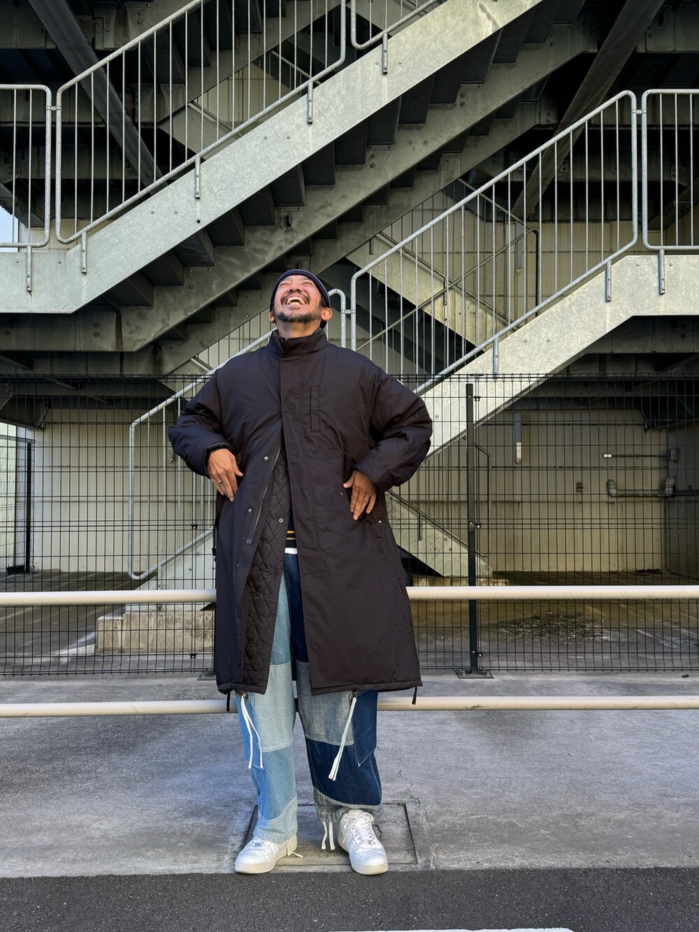 ブラック系のモッズコート、ブルー系のデニムパンツ、ホワイト系のスニーカーを着用したメンズの秋コーディネートの3枚目の写真