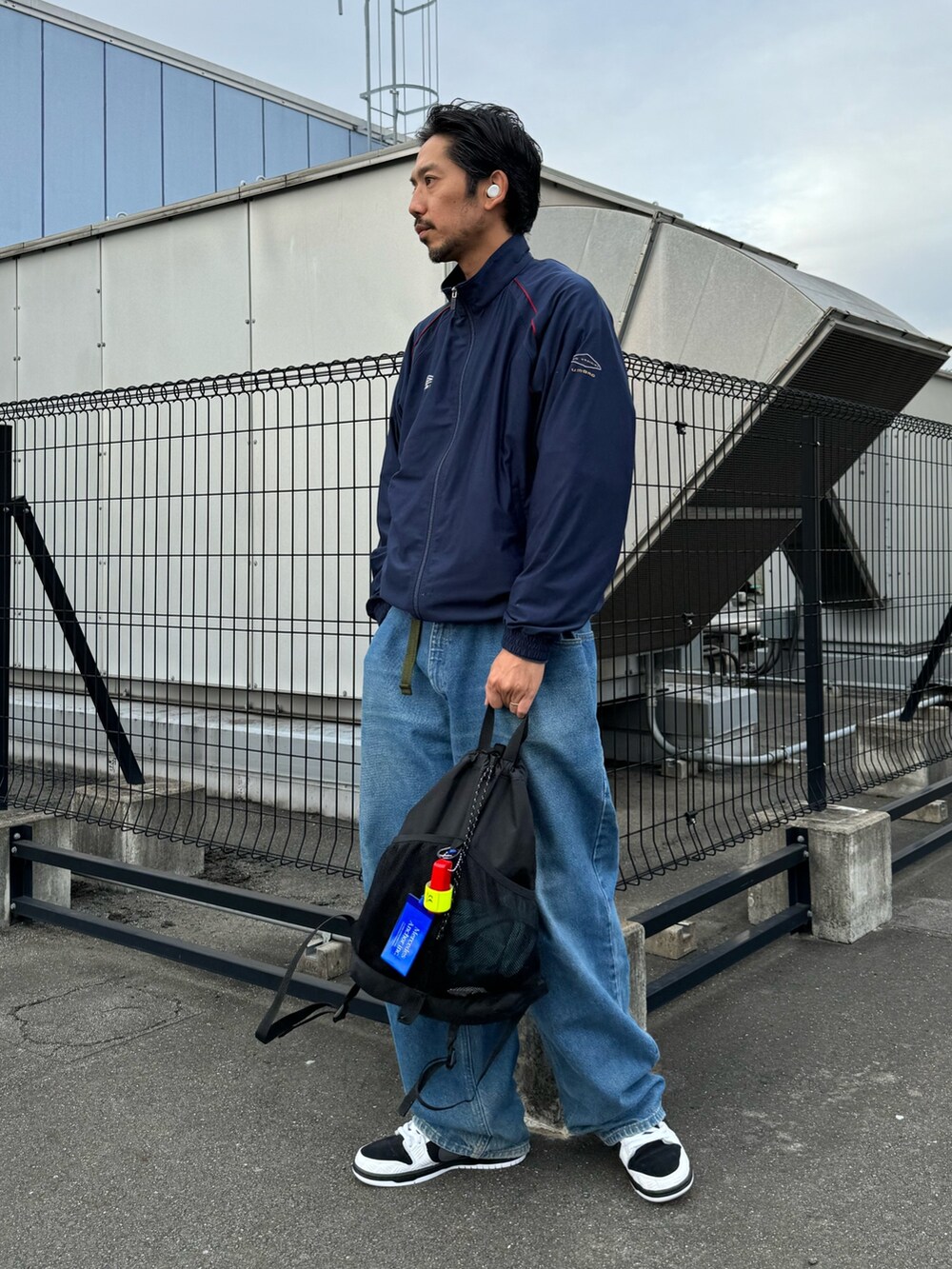 ホワイト系のシューズ、ブラック系のバックパック/リュック、ブルー系のデニムパンツを着用したメンズの秋コーディネートの4枚目の写真