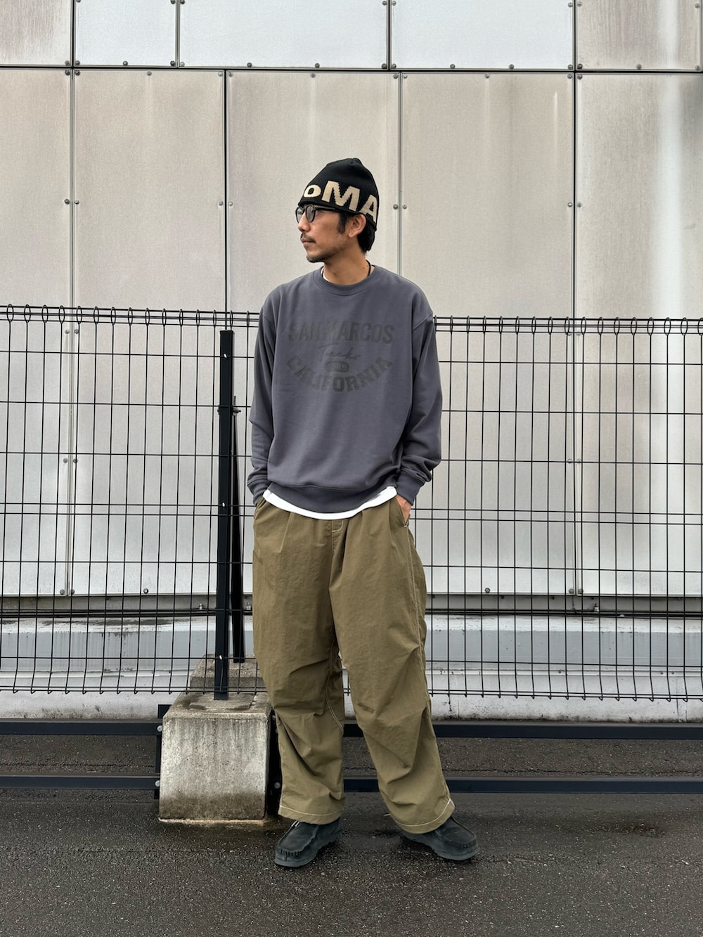 グレー系のスウェット、ブラック系のカーゴパンツ、ブラック系のブーツを着用したメンズの秋コーディネートの2枚目の写真