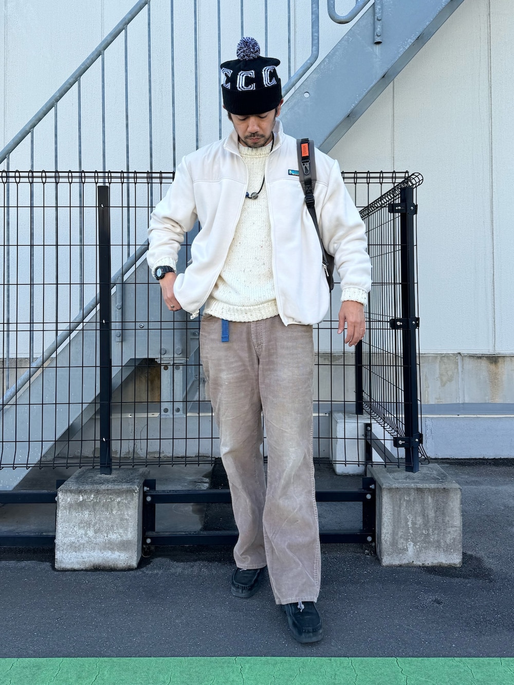グレー系のブルゾン、ホワイト系のニット/セーター、ベージュ系のパンツを着用したメンズの冬コーディネートの2枚目の写真