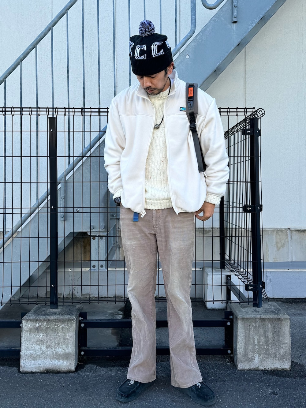 グレー系のブルゾン、ホワイト系のニット/セーター、ベージュ系のパンツを着用したメンズの冬コーディネートの6枚目の写真