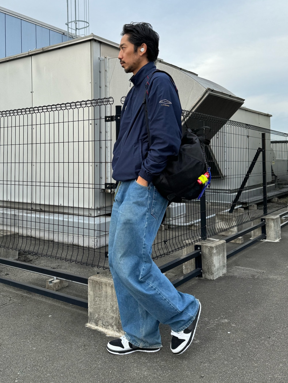 ホワイト系のシューズ、ブラック系のバックパック/リュック、ブルー系のデニムパンツを着用したメンズの秋コーディネートの6枚目の写真