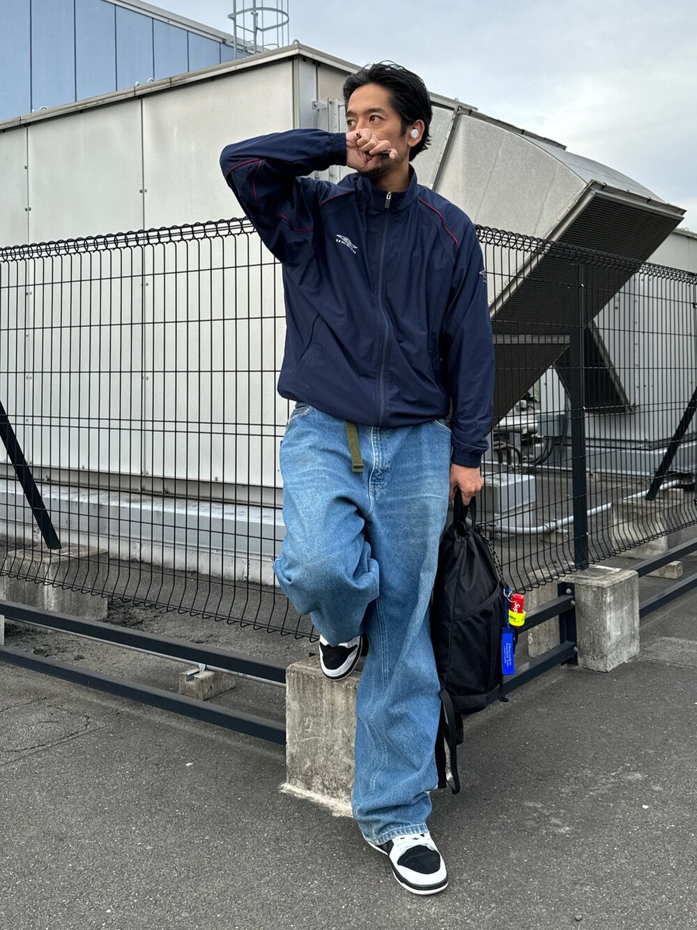 ホワイト系のシューズ、ブラック系のバックパック/リュック、ブルー系のデニムパンツを着用したメンズの秋コーディネートの5枚目の写真