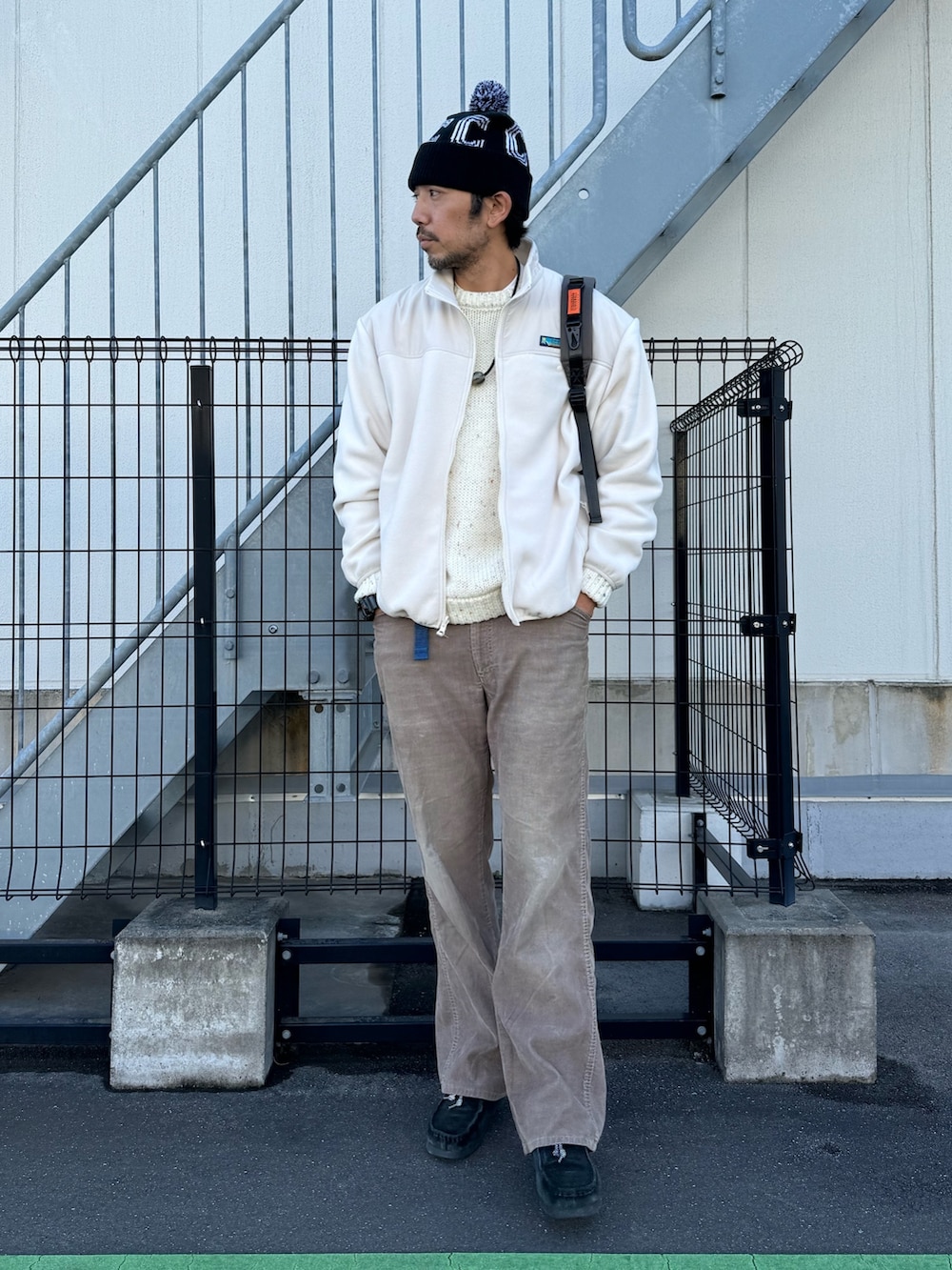 グレー系のブルゾン、ホワイト系のニット/セーター、ベージュ系のパンツを着用したメンズの冬コーディネートの4枚目の写真