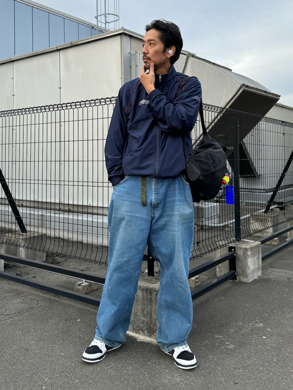 ホワイト系のシューズ、ブラック系のバックパック/リュック、ブルー系のデニムパンツを着用したメンズの秋コーディネートの7枚目の写真