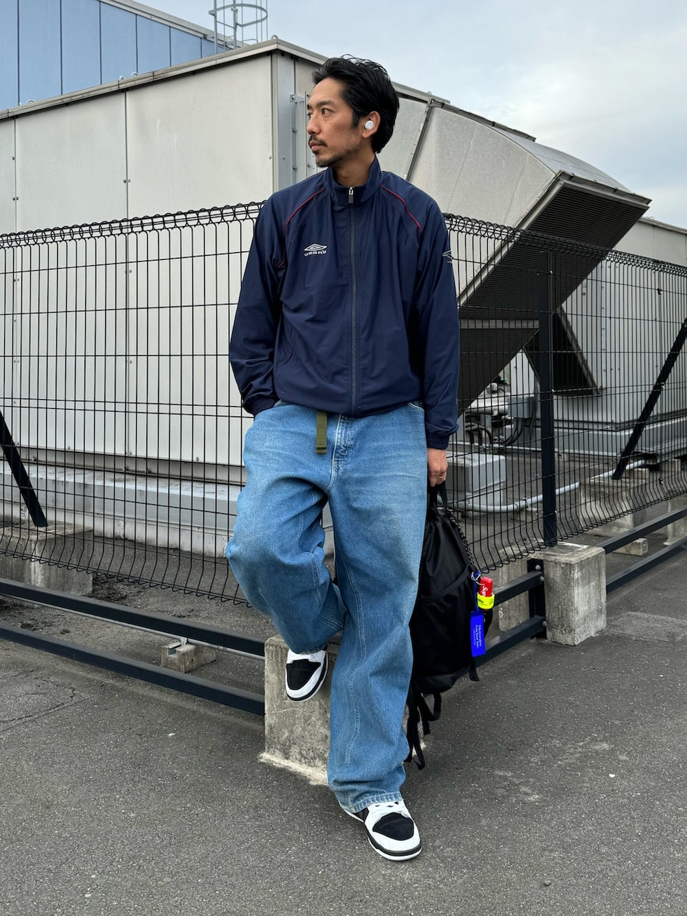 ホワイト系のシューズ、ブラック系のバックパック/リュック、ブルー系のデニムパンツを着用したメンズの秋コーディネートの2枚目の写真