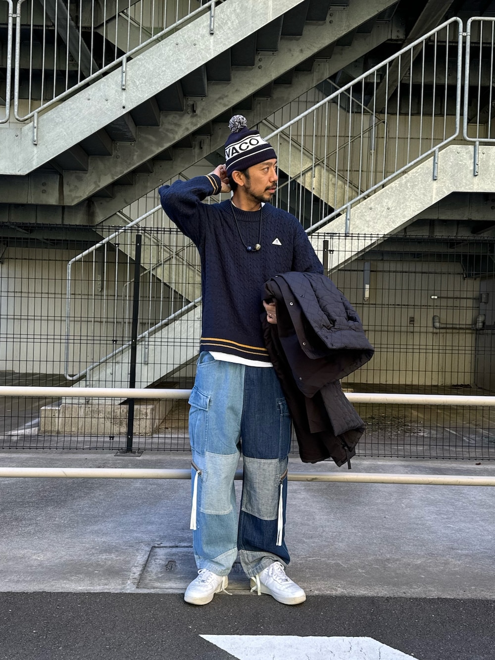 ブラック系のモッズコート、ブルー系のデニムパンツ、ホワイト系のスニーカーを着用したメンズの秋コーディネートの9枚目の写真