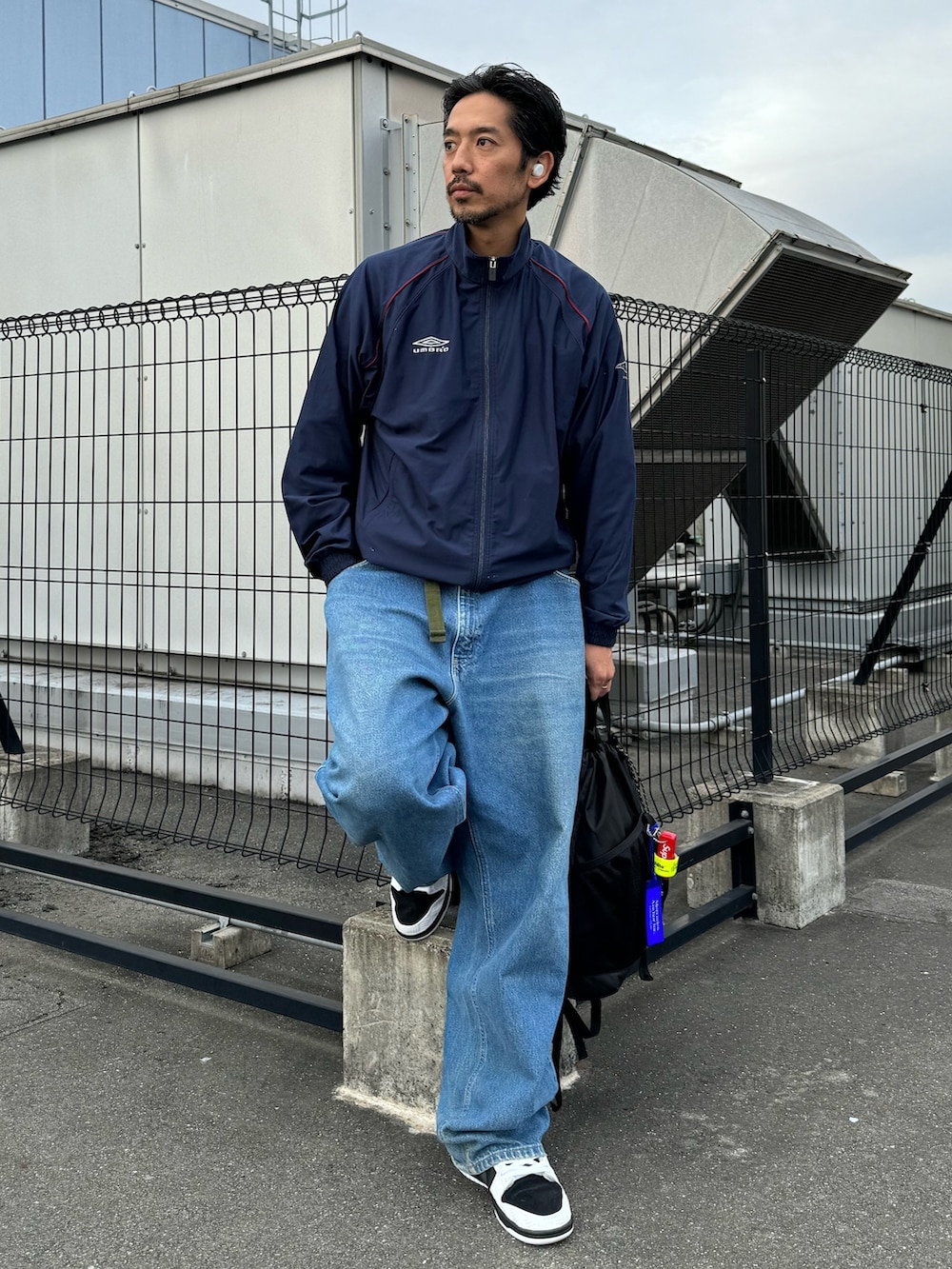 ホワイト系のシューズ、ブラック系のバックパック/リュック、ブルー系のデニムパンツを着用したメンズの秋コーディネートの3枚目の写真