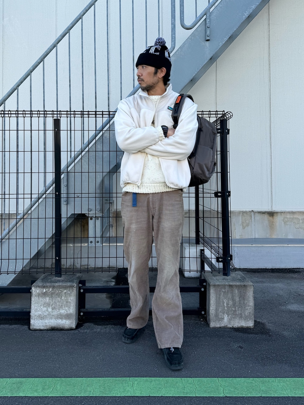 グレー系のブルゾン、ホワイト系のニット/セーター、ベージュ系のパンツを着用したメンズの冬コーディネートの3枚目の写真