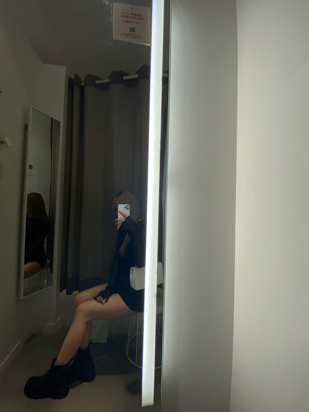 ブラック系のブーツ、ホワイト系のバッグ、ブラック系のパンツを着用したレディースの秋コーディネートの2枚目の写真