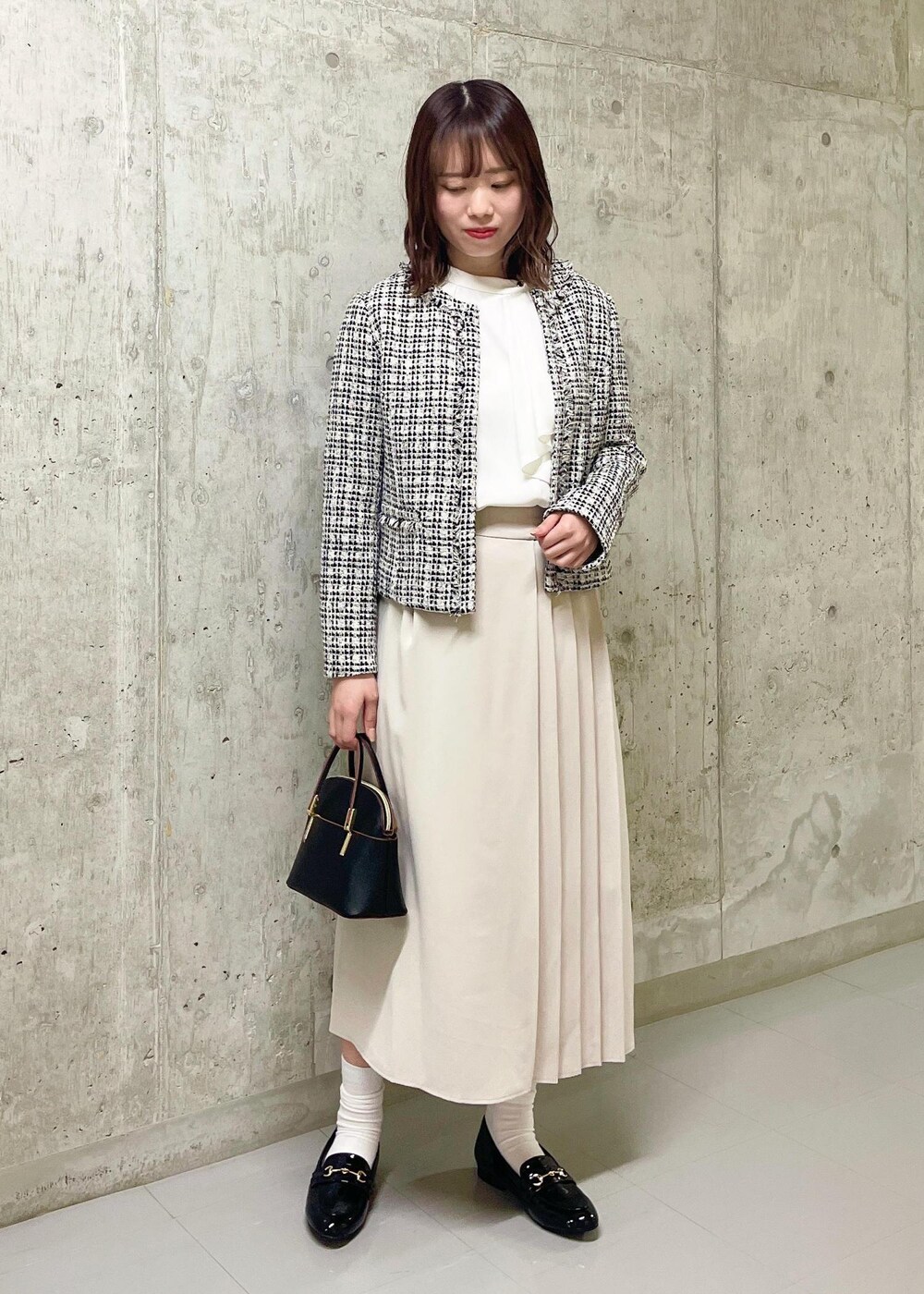 ブラック系のローファー、ブラック系のノーカラージャケット、ブラック系のショルダーバッグを着用したレディースの春コーディネートの2枚目の写真