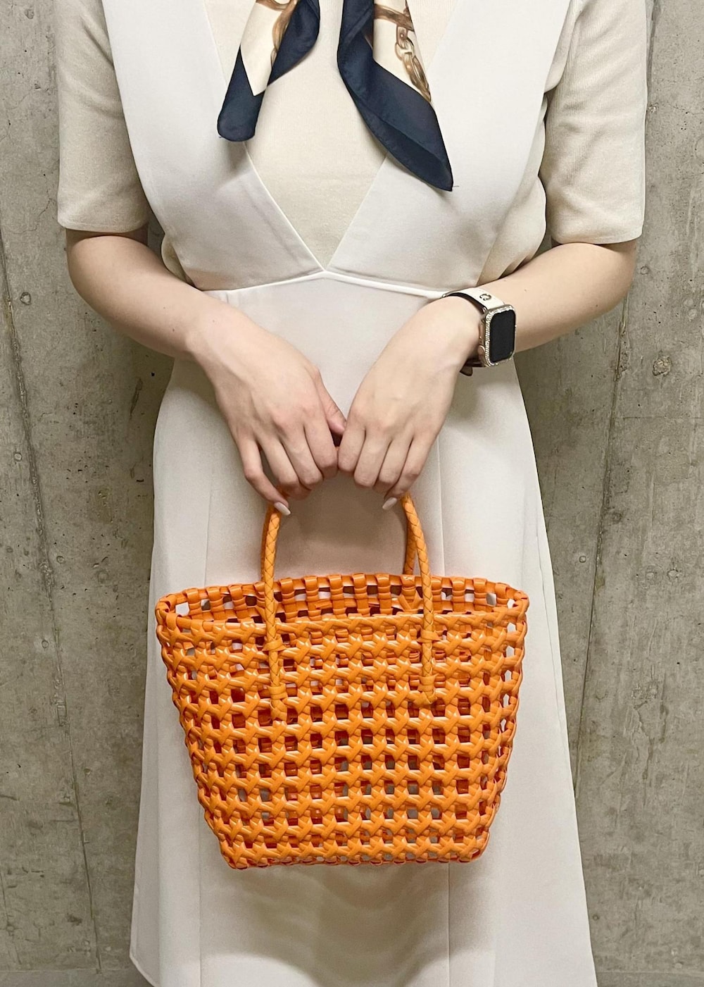 オレンジ系のトートバッグ、ホワイト系のローファー、ホワイト系のニット/セーターを着用したレディースの夏コーディネートの4枚目の写真