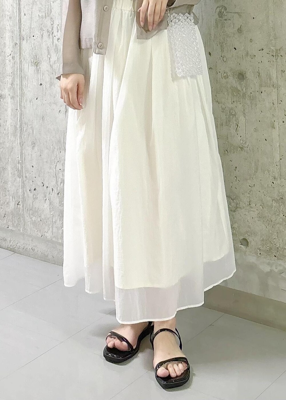 ホワイト系のスカート、ブラック系のTシャツ/カットソー、ブラック系のサンダルを着用したレディースの夏コーディネートの6枚目の写真