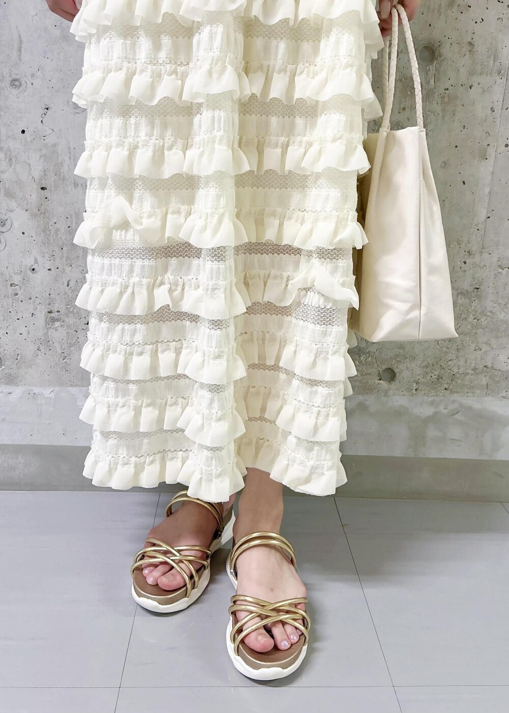 ホワイト系のワンピース、ゴールド系のサンダル、ブラウン系のテーラードジャケットを着用したレディースの夏コーディネートの7枚目の写真