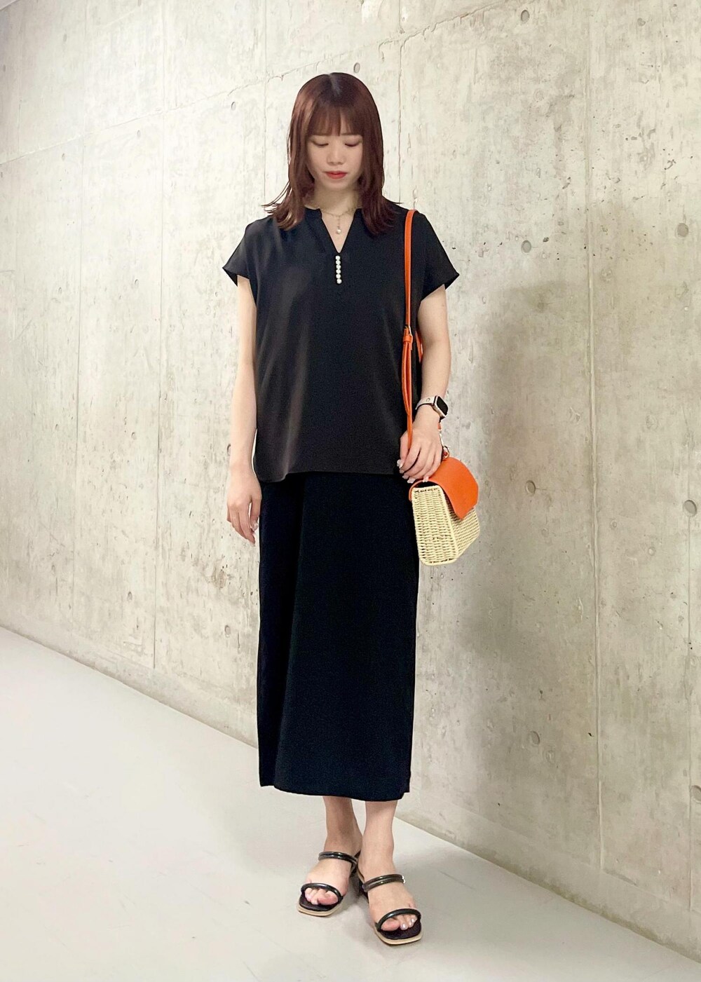 オレンジ系のショルダーバッグ、ブラック系のサンダル、ブラック系のワンピースを着用したレディースの夏コーディネートの2枚目の写真