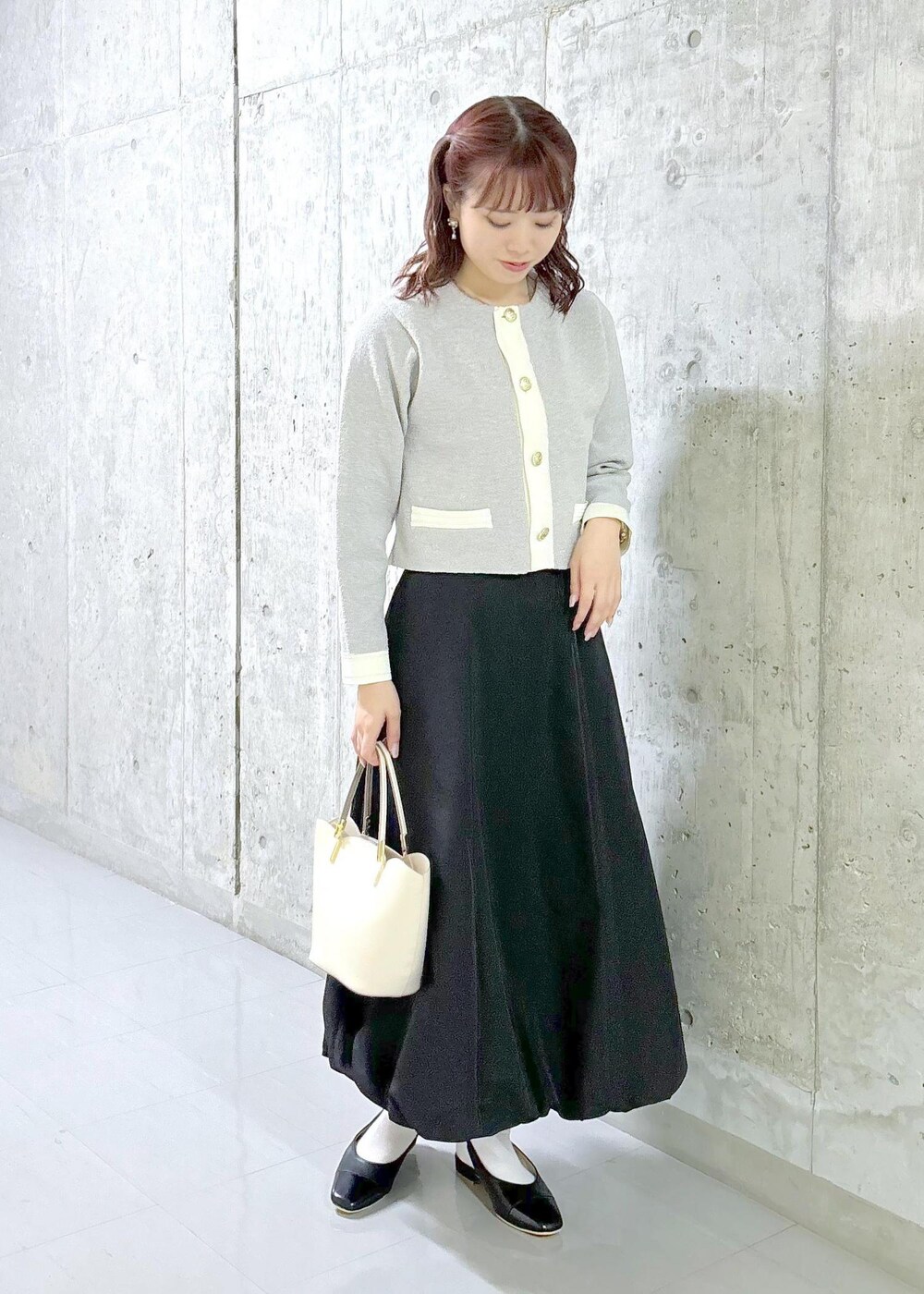 ブラック系のスカート、グレー系のカーディガン/ボレロ、ブラック系のパンプスを着用したレディースの秋コーディネートの2枚目の写真