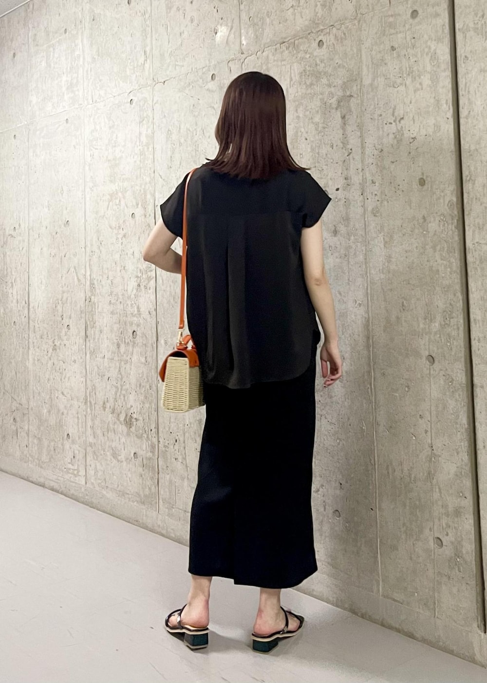 オレンジ系のショルダーバッグ、ブラック系のサンダル、ブラック系のワンピースを着用したレディースの夏コーディネートの3枚目の写真