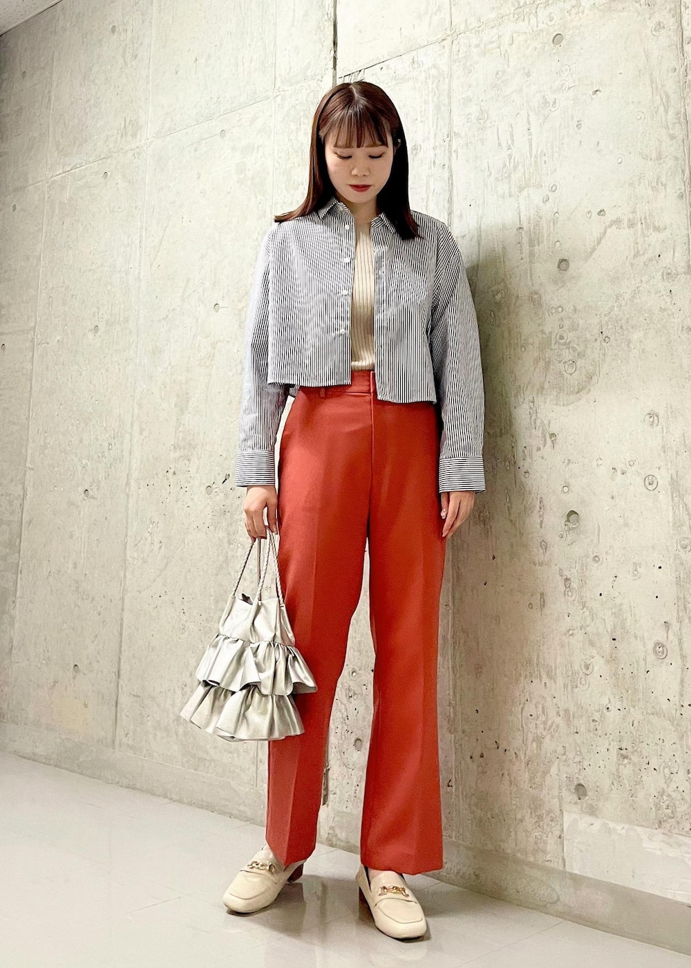 ホワイト系のローファー、シルバー系のトートバッグ、ベージュ系のニット/セーターを着用したレディースの秋コーディネートの2枚目の写真