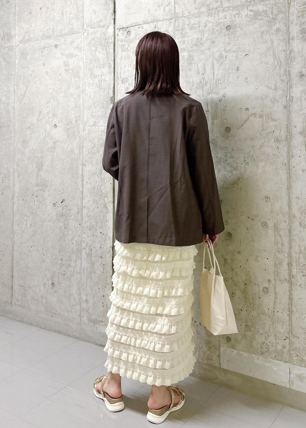 ホワイト系のワンピース、ゴールド系のサンダル、ブラウン系のテーラードジャケットを着用したレディースの夏コーディネートの5枚目の写真