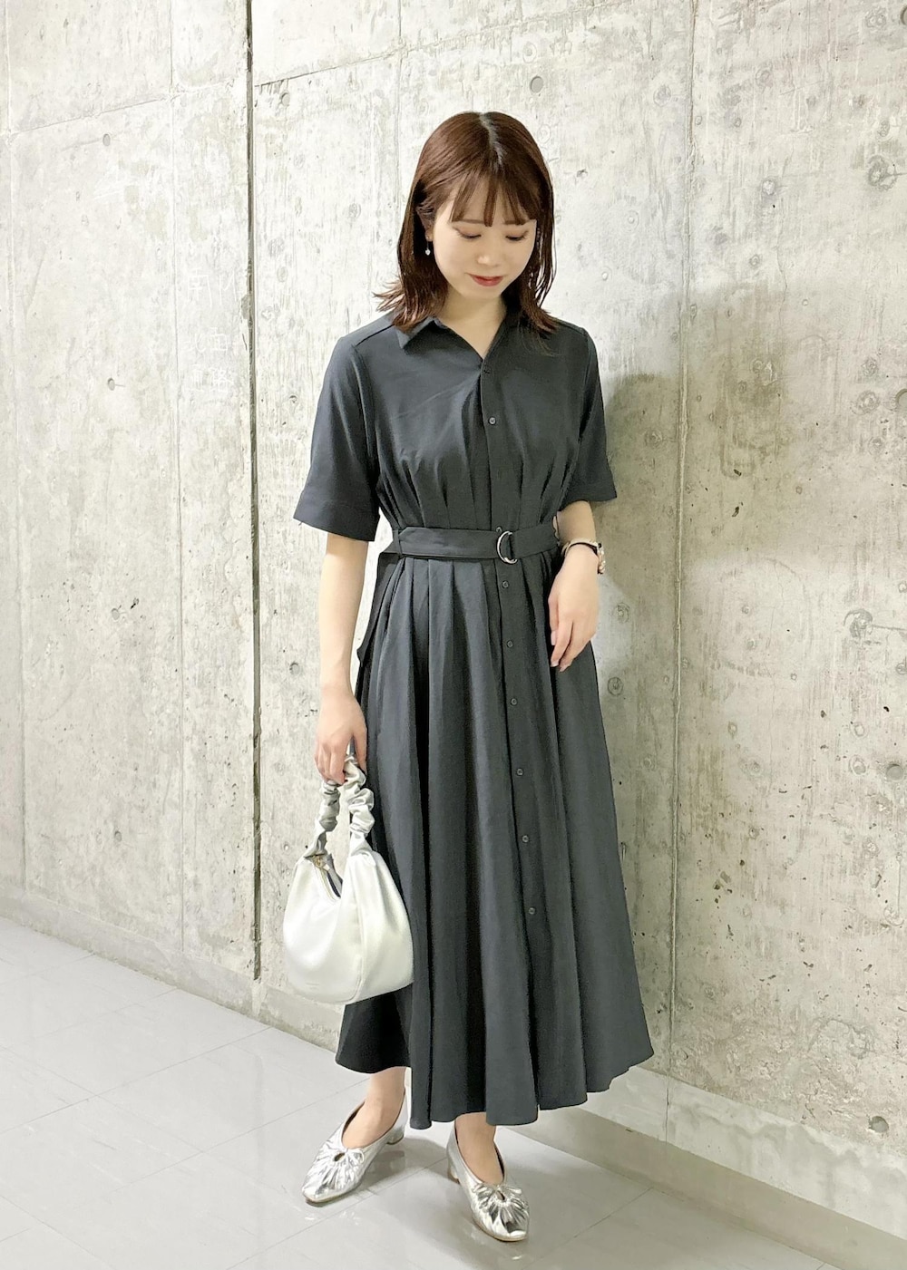 シルバー系のパンプス、グレー系のシャツワンピース、シルバー系のハンドバッグを着用したレディースの夏コーディネートの2枚目の写真