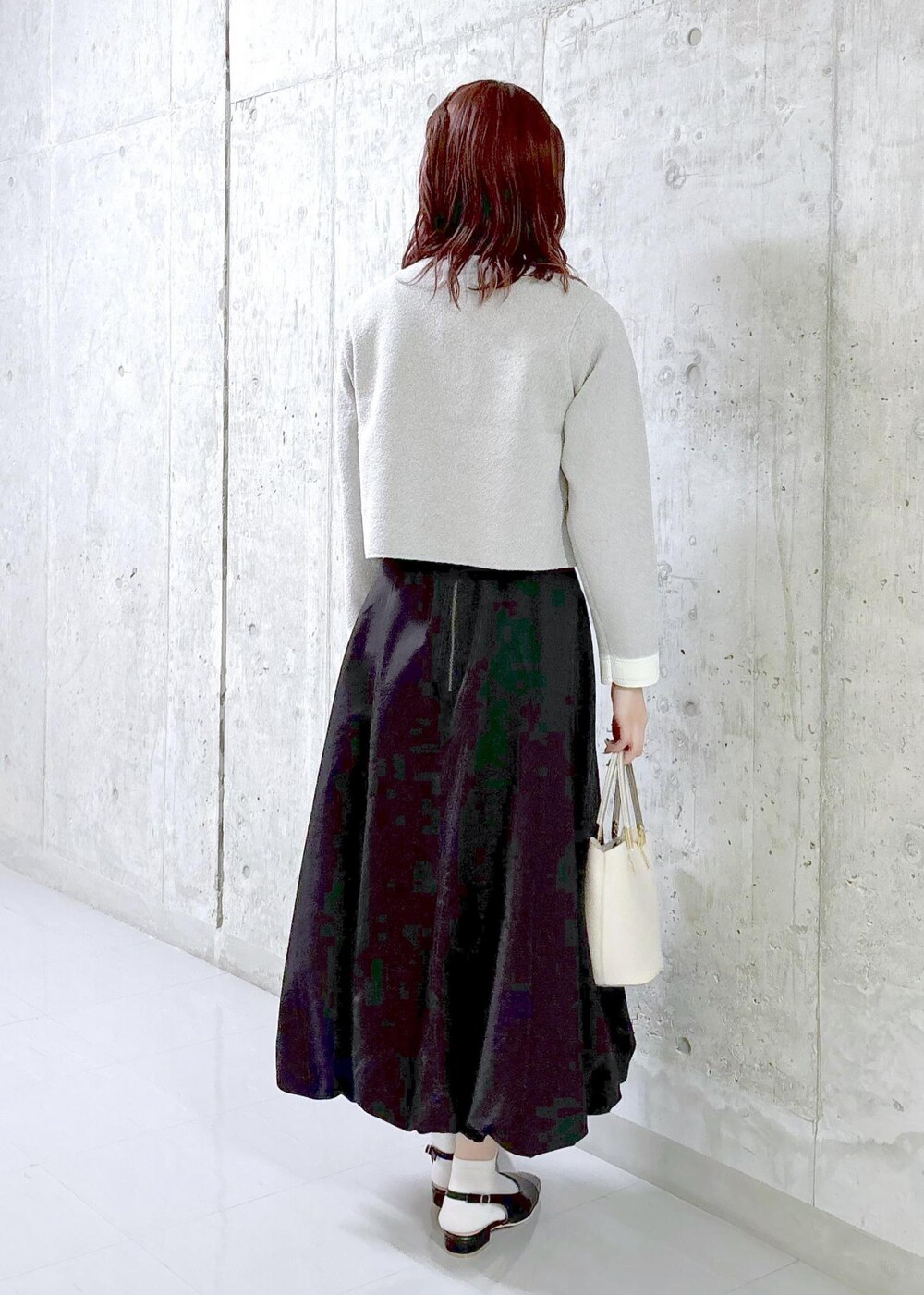 ブラック系のスカート、グレー系のカーディガン/ボレロ、ブラック系のパンプスを着用したレディースの秋コーディネートの3枚目の写真