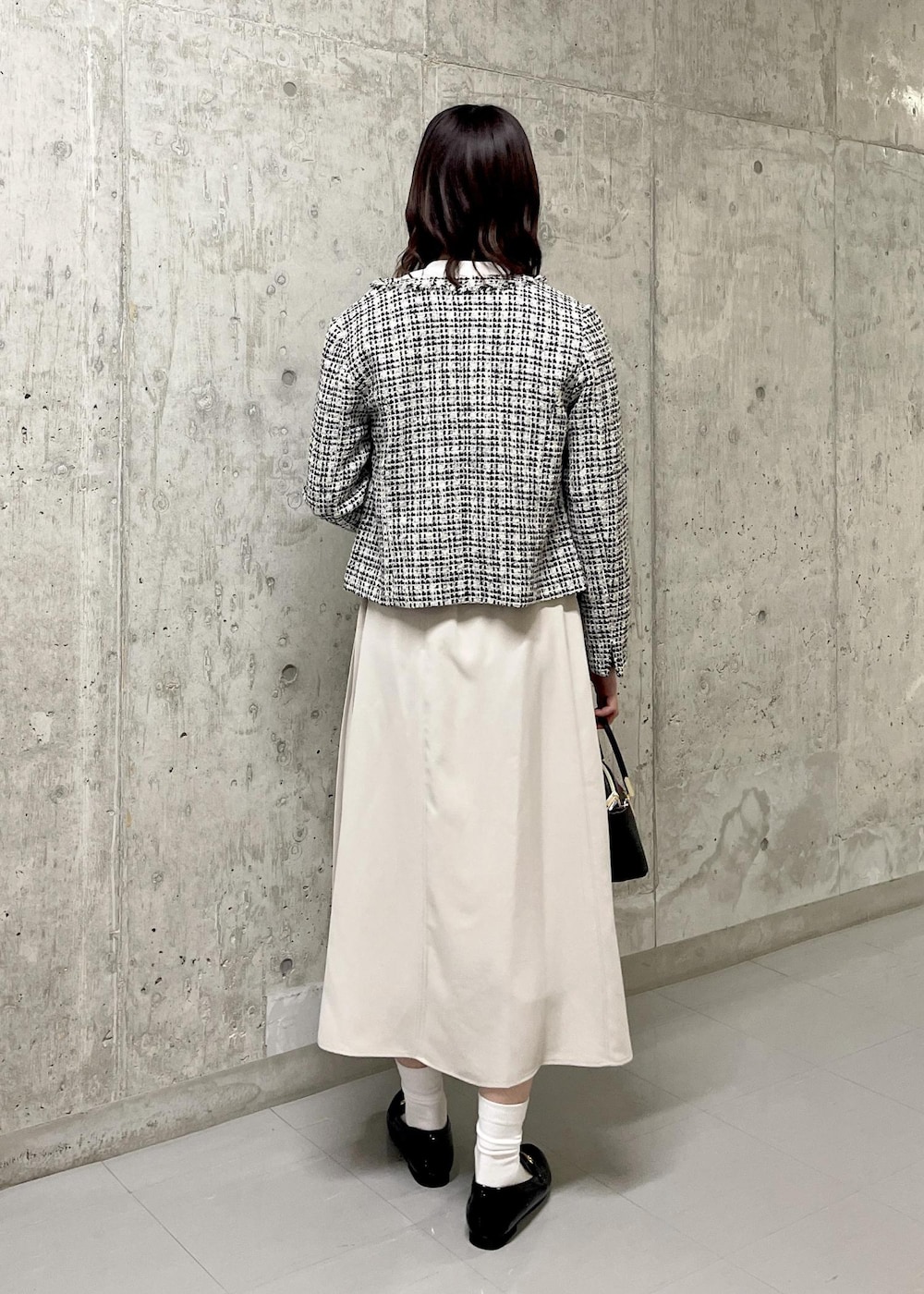 ブラック系のローファー、ブラック系のノーカラージャケット、ブラック系のショルダーバッグを着用したレディースの春コーディネートの3枚目の写真